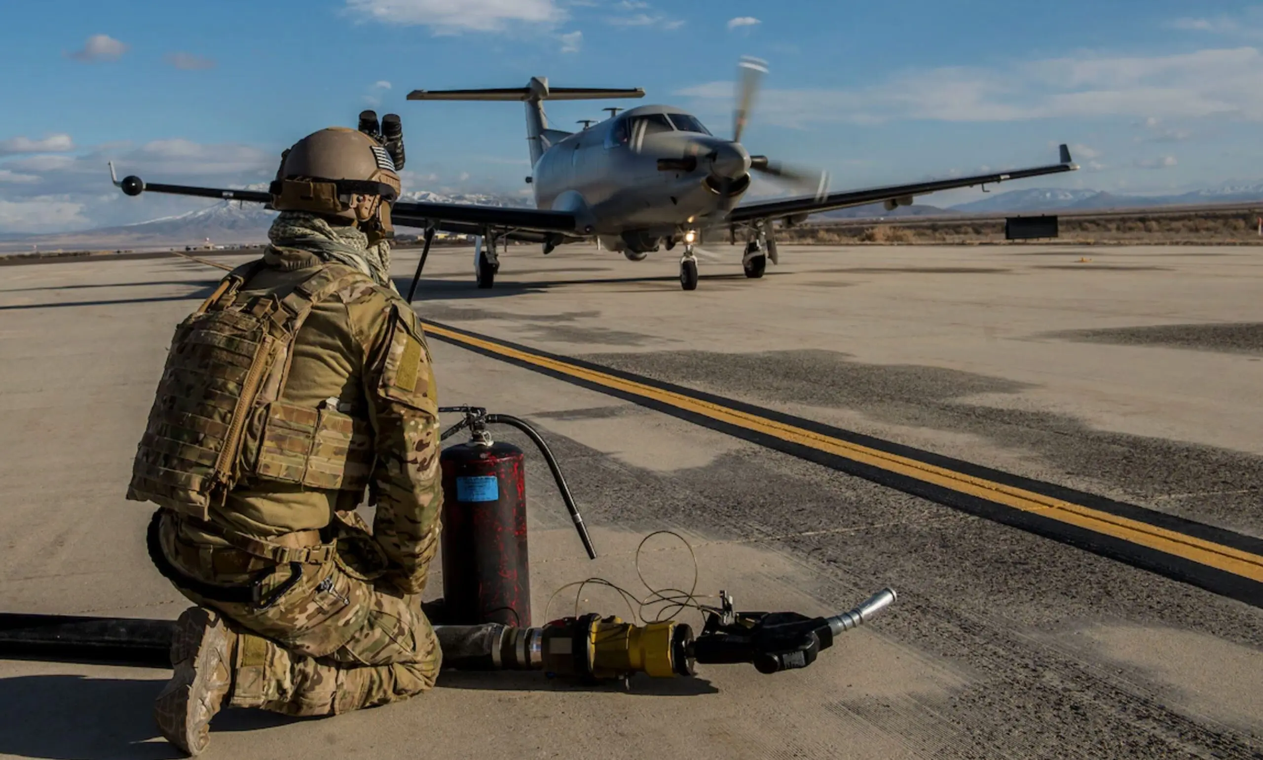 A soldier sitting on the ground next to an airplane.