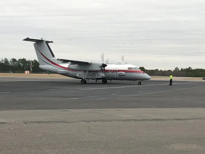 A large airplane on the runway with a person standing next to it.