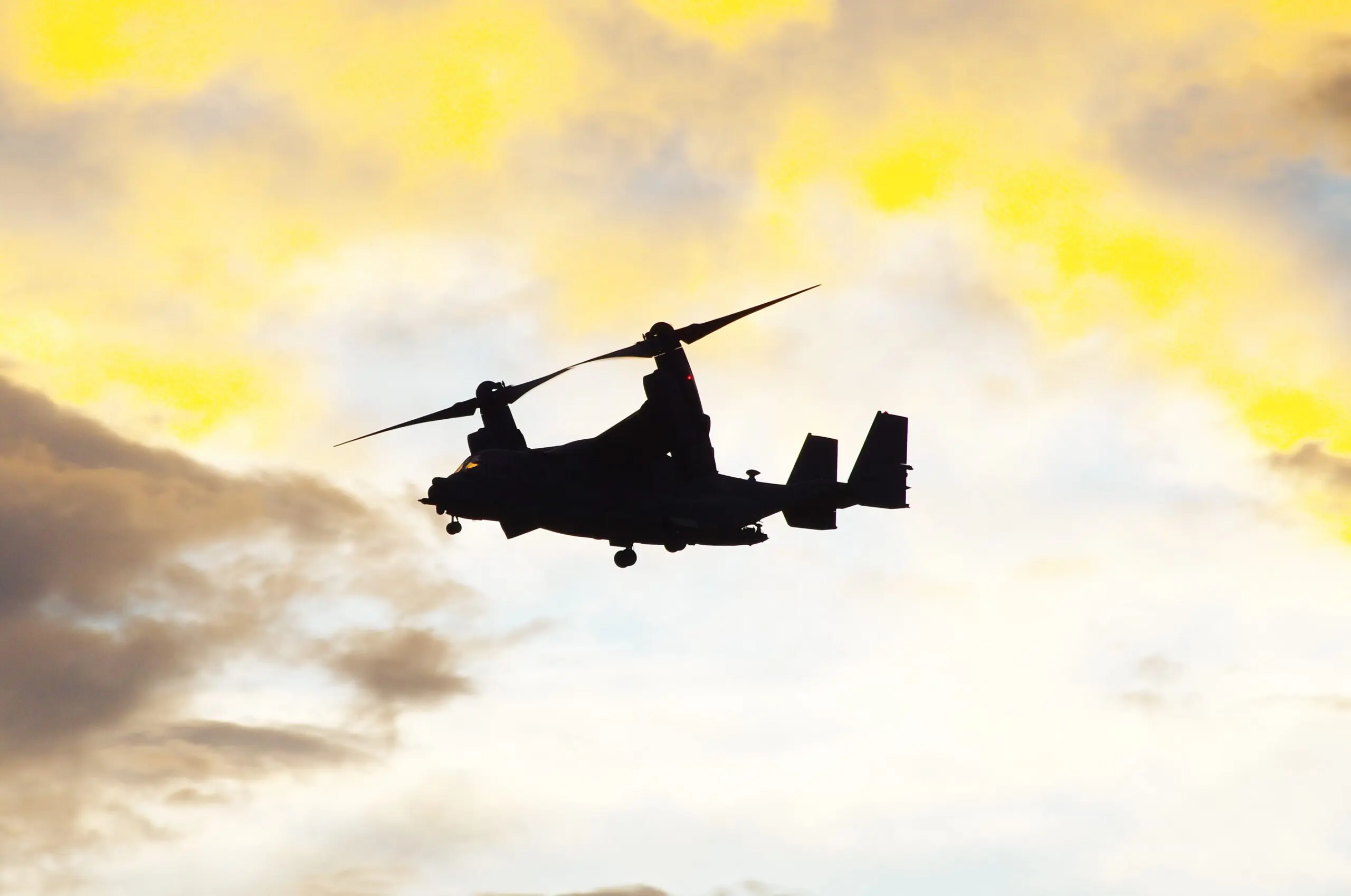 A helicopter flying in the sky with clouds behind it.