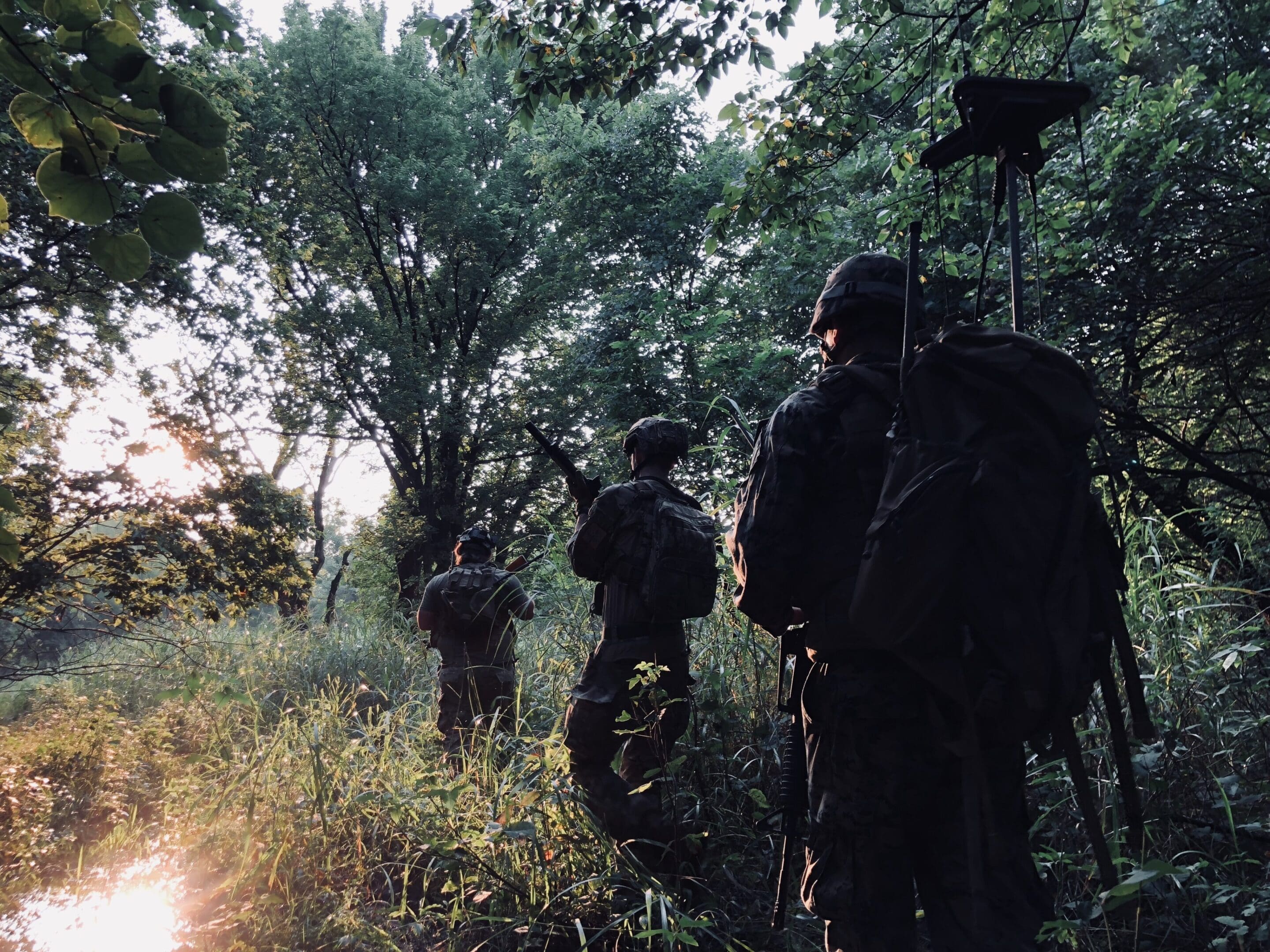 A group of men in the woods with guns.