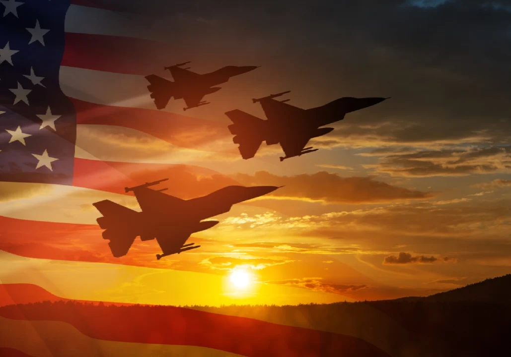 Three fighter jets fly in formation against a sunset backdrop with a semi-transparent American flag overlay.